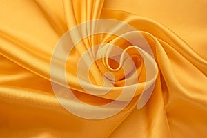 Silk background. Folds of yellow satin. Smooth shiny fabric texture, abstract bright wallpaper. Crumpled textile surface