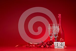 Silk hearts, champagne bottle and flutes, calendar with date 14 february on red background with copy space. Valentine`s Day