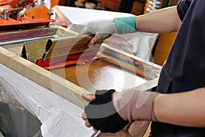 silk screen printing. male hand with a squeegee. serigraphy production. printing images on clothes by silk screen method in a