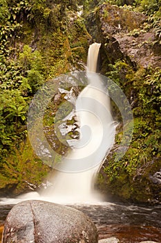 Silky forest waterfall cascading down rocky slope