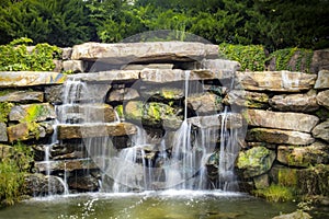 Silky waterfall over mossy rocks in park colorful with slow shutter speed