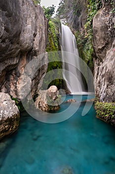 Silky waterfall wedged between rock walls with turquoise water