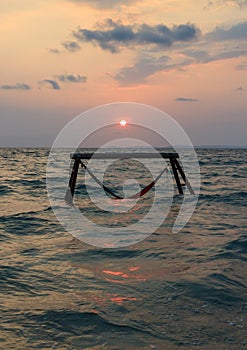 Sillhouette of hammock in sea on sunset