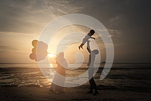 Sillhouette of happy asian family having fun time at the beach with sunset view as background