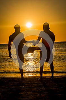 Sillhouettes of two men in the beach during sunset