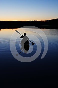 Sillouette of man kayaking on lake photo