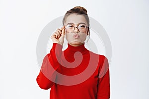 Silly blond girl in glasses pucker lips, making kissing face and looking happy at camera, picking new eyewear, standing