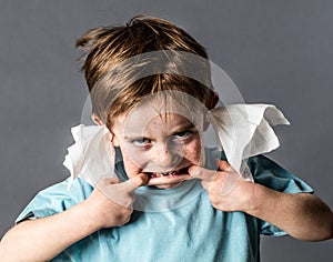 Silly kid with tissue in ears making grimace, not listening