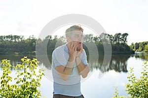 Silly man making funny face or grimace over nature background