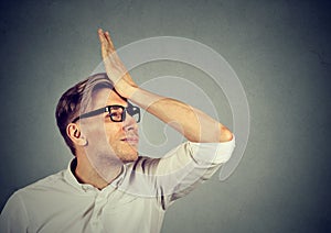 Silly man slapping hand on head having duh moment