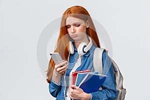 Silly sad and gloomy pouting girl with red foxy hair, frowning sighing and looking with regret smartphone screen