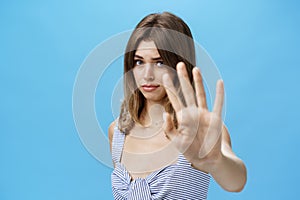 Silly and shy insecure attractive girl pulling hand towards to cover face from camera making moody timid expression