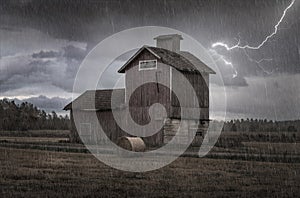 Silo barn in the rain with lightning in the sky and dark clouds in a field with a bale of hay