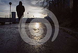 Silhouette of man walking on a damp street a gloomy day in late autumn/winter,