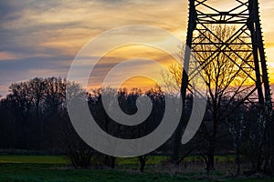 Silouette of a power pole with orange and yellow sky in the background