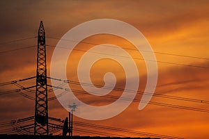 Silouette of a power pole with orange and yellow sky in the background