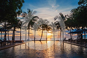 Silouette swimming pool with sunbed and coconut tree at seaside resort