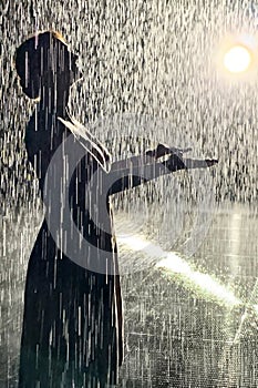 Siluette of a woman under artificial rain in rain room