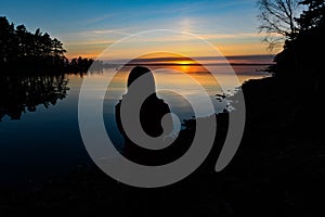 Siluette of a young person standing infront of a sunset photo