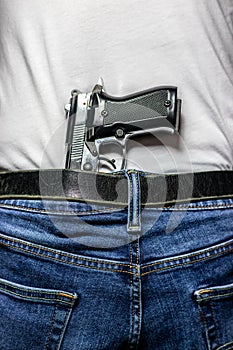 Silver 9mm handgun in waistband from behind