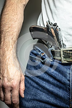 Silver 9mm handgun in waistband from front with arm and hand on