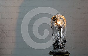 A silver angel sculpture holding a lighted tea light candle, a christmas and spiritual tradition