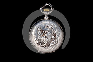 Silver antique pocket watch with a closed lid on an isolated black background. Round retro pocketwatch with a pattern of