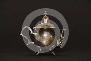 Silver antique teapot on a black background. A beautiful antique silver teapot. The kettle is silver.