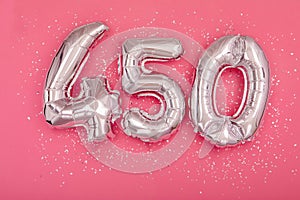 Silver balloon showing number 450 four hundred and fifty pink background