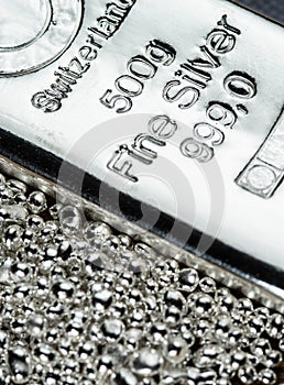 A silver bar weighing 500 grams  and a pile of silver grains.