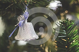 Silver bells with blue satin ribbon bow hang on the Christmas tree