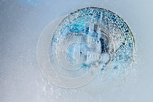 Silver Bitcoin, bit coin online digital currency frozen in the blue ice. Concept of block chain, crypto market crash. Frozen