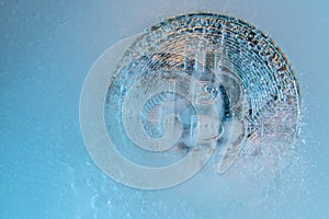 Silver Bitcoin, bit coin online digital currency frozen in the blue ice. Concept of block chain, crypto market crash. Frozen