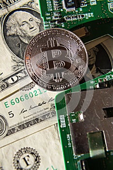 Silver bitcoin coin with dollars and computer motherboard, cryptocurrency mining concept