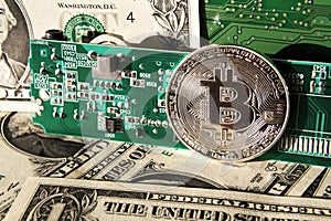 Silver bitcoin coin with dollars and computer motherboard, cryptocurrency mining and investing