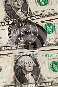 Silver bitcoin coin lying on United States dollars, cryptocurrency concept
