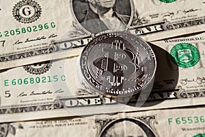 Silver bitcoin coin lying on United States dollars, cryptocurrency concept