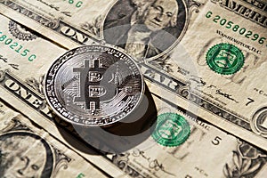 Silver bitcoin coin lying on United States dollars, cryptocurrency concept