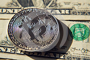 Silver bitcoin coin lying on United States dollars, cryptocurrency concept