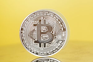 Silver Bitcoin coin on yellow . Electronic money