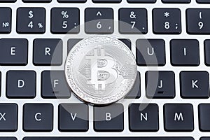 Silver bitcoin on computer key board close-up.