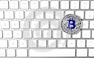 Silver bitcoin on computer keyboard. Space for text