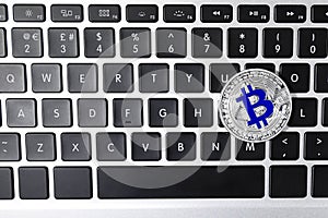Silver bitcoin on computer keyboard. Space for text