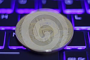 Silver bitcoin on illuminated computer keyboard