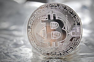 Silver Bitcoin Standing.Blockchain technology. Coin on a foil texture