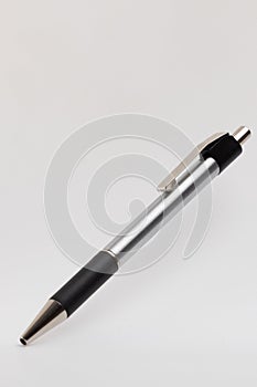 A silver and black ballpoint pen is depicted on a light background. The pen