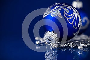 Silver and blue christmas ornaments on dark blue background with space for text