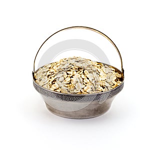 A silver bowl of uncooked rolled oats isolated on white background