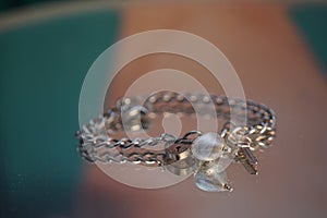a silver bracelet with charms and two pearls in it sitting on a table