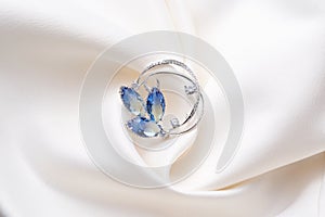 Silver brooch with blue iridescent crystals, isolated on white background.
